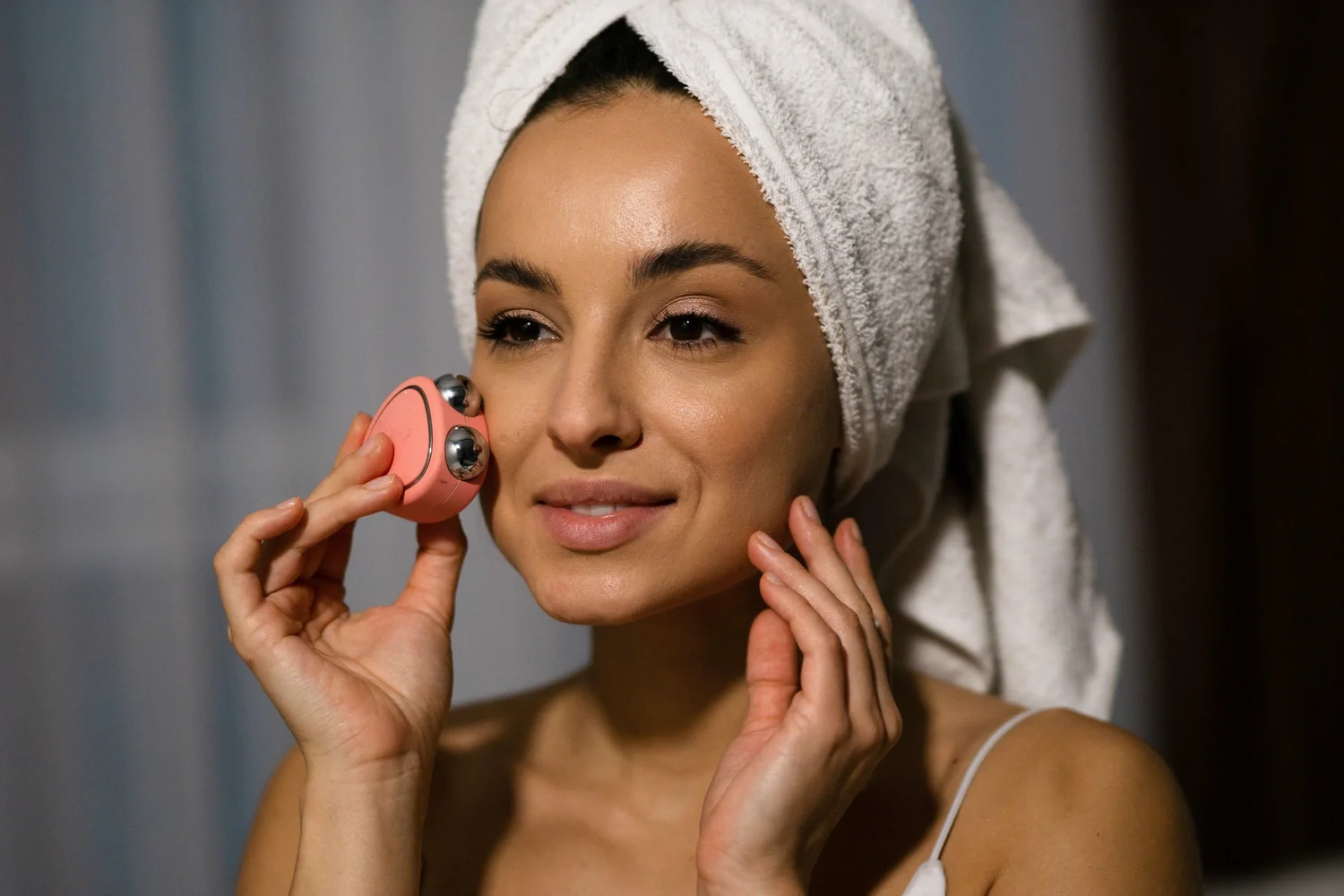 Smart Home Devices Skincare Tips – woman using a facial skincare device with a towel wrapped around her head for a modern beauty routine