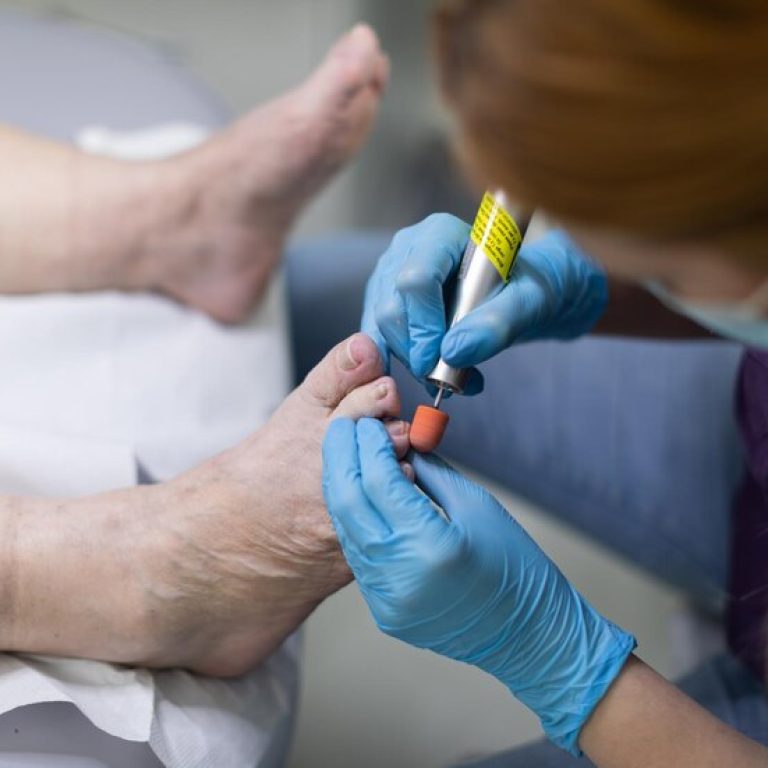 podiatrist-leans-clients-feet-performs-pedicure_357949-3002